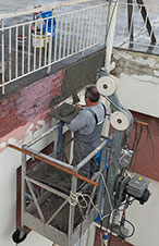 Αντιδιαβρωτική προστασία ράβδων οπλισμού σκυροδέματος, τσιμεντοκονίαμα και ελαιοχρωματισμός. Βάψιμο με κρεμαστό καλάθι εργασίας με πρόβολο αντιστήριξης, χωρίς χρήση σκαλωσιάς.